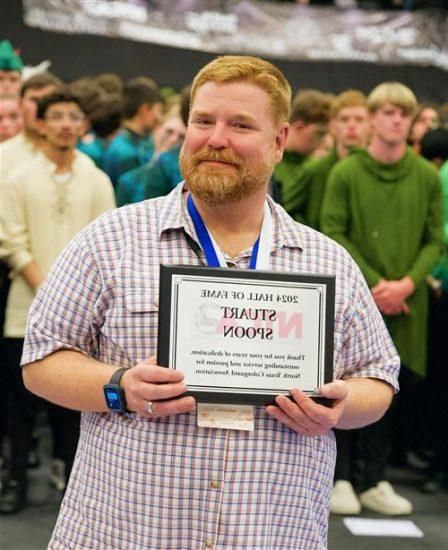 A person posing with an award plaque.